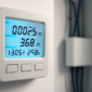 Slimme energiemeter met digitaal display gemonteerd op een witte muur in een meterkast